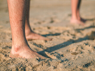 Mans standing by barefoot on the sand beach. Feet standing on the beach and copy space.