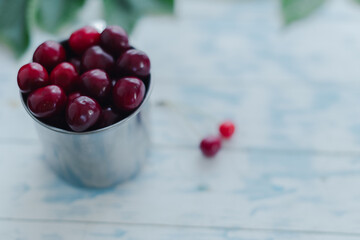 Cherries in a steel mug on a wooden background