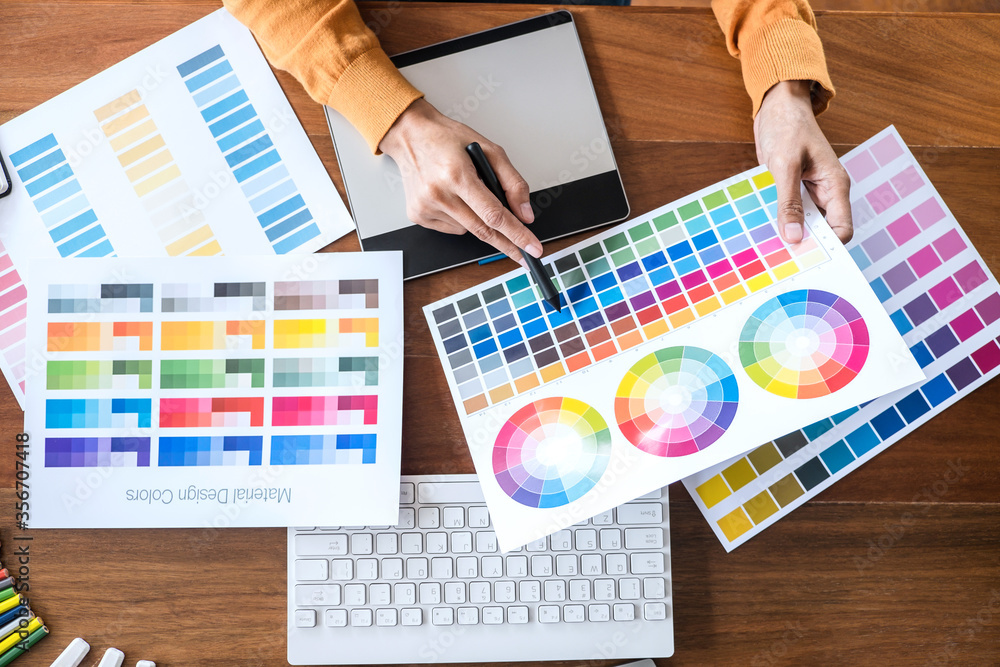 Poster image of female creative graphic designer working on color selection and drawing on graphics tablet 