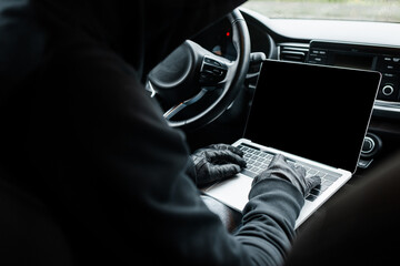 Selective focus of robber in leather gloves using laptop in car - obrazy, fototapety, plakaty