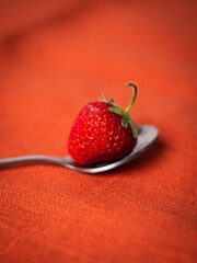 Close-up Of Strawberry On Spoon Over red Background
