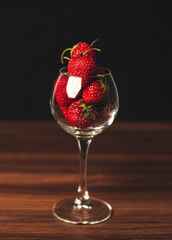 Fresh strawberries in wine glass on table. Ripe strawberry closeup. Sweet summer harvest. Juicy dessert. Healthy food. Red berries in glass vase on unfocused background. Freshness concept.