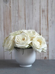 Flower background.A bouquet of white roses in a large white tea Cup on a wooden background.petals