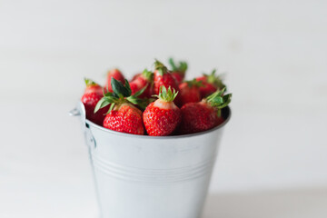 Juicy fresh strawberries in a metal bucket on a white background