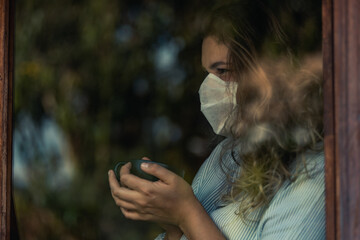.woman looking out the window with face mask