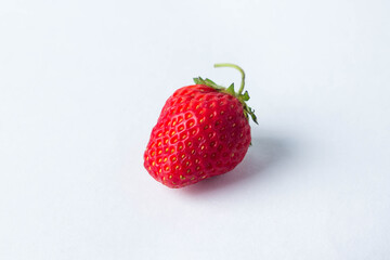 One strawberry on a white background. Red, ripe and juicy strawberries.