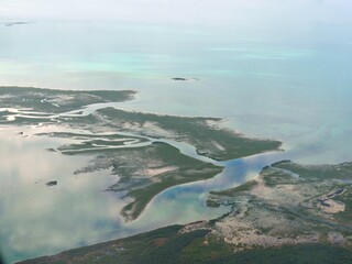 Beautiful layout of the Exuma Cays surrounded by clear blue waters of the Bahamas seen from an airplane window.