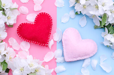 Two handmade hearts on a pink-blue background with a frame of white spring flowers and petals. Greeting card for Women's Day, Mother's Day and Valentine's Day. Flyer for wedding day.