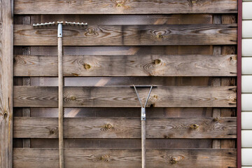 rake and chopper hanging on a wooden wall from old textured boards