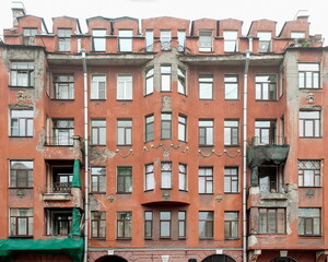 The facade of an old residential building with crumbling plaster. Panorama.