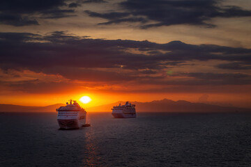 A sunset with cruise ships anchored in the foreground.