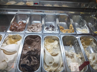 Italian ice cream on the counter with different varieties scoopable flavors, sorbet, chocolate, toppings, coffee