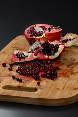 opened pomegranate on wooden cutting board and black background