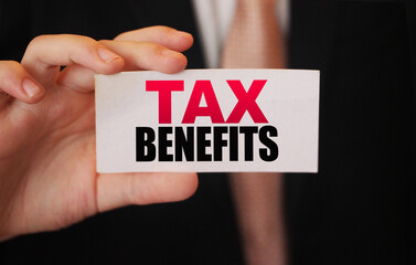 Businessman shows a card with text tax benefits. Taxes and fees policy regulation concept