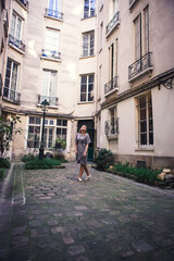 Fototapeta na wymiar woman in gray dress standing in courtyard of house of European cities. 