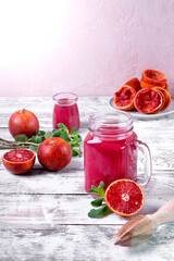 Smoothie with blood orange juice in the mason jar on the white wooden table