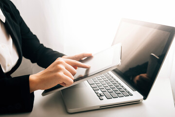 businesswoman hand working with laptop computer, tablet and smart phone in modern office with virtual icon diagram at modernoffice in morning light