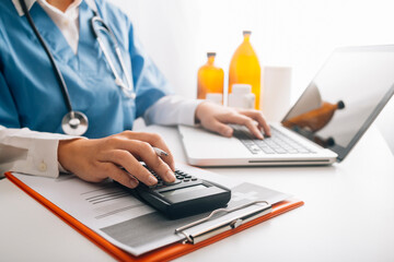 Healthcare costs and fees concept.Hand of smart doctor used a calculator and smartphone, tablet for...