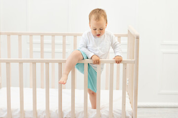 baby climbs out of the crib, baby boy 2 years old in the crib
