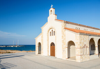 Fototapeta premium New beautiful church on a background of blue sea and yachts.