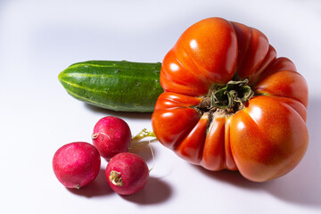 large red tomato cucumber and radish on a white background