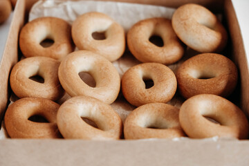 Drying or round bagels in a paper box on a white wooden background. Top view. Copy, empty space for text