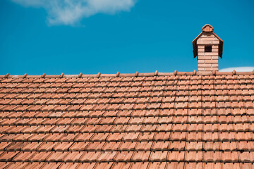 Old roof tiles on the roof of an house with chimney on sky background. Place for text or advertising