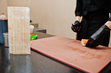 Close up hands of professional chef wear in black gloves making sushi and rolls in a restaurant kitchen of japanese traditional food.