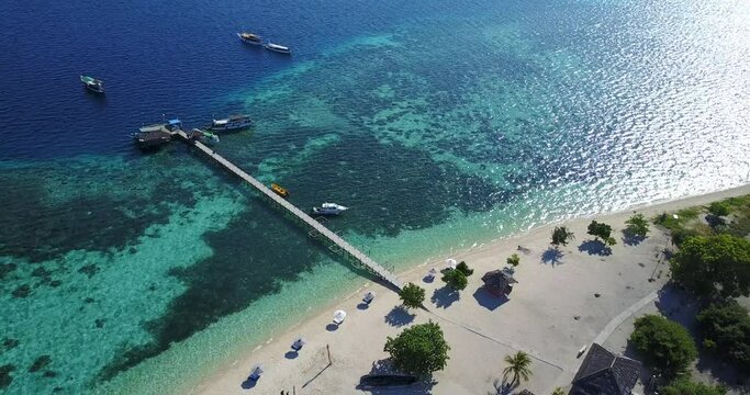 High aerial day view of the coral reef surrounding Kanawa Island and its beautiful white sand beach, near the city of Labuan Bajo on Flores, Indonesia 