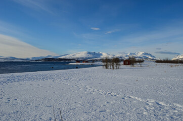blue sea with snowy sea shore and mountain with red huts
