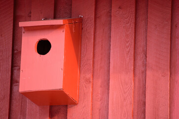 red bird house on barn wall in sunshine
