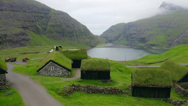 4k drone flight moving to the side footage (Ultra High Definition) of Saksun village with typical turf-top houses and Saksunar Kirkja, Faroe Islands. Misty morning view of Streymoy island, Denmark.