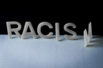 Drop racism. The word written with plastic letters, the last letter is turned over before falling....