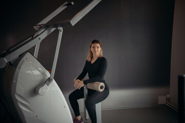 Modern gym - a young woman sitting on the strength training machine