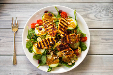 Appetizing, spring vegetarian vegetable salad with halloumi cheese, cherry tomatoes, spinach, cranberry, pumpkin seeds, sunflower seeds and nuts.