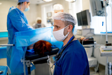 Male doctor is working in an operation room. Man in scrubs while operating. Modern surgery concept.