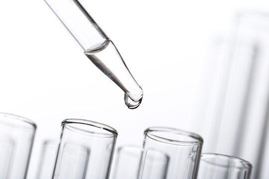 pipette with a drop and scientific laboratory test tubes in a research laboratory.