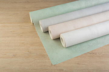 rolls of multi-colored paper wallpaper on a wooden table