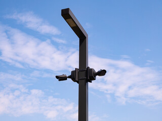 Outdoor surveillance video cameras on street lamp against blue sky with copy space for text. Security concept.