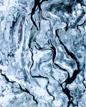 Aerial view of river Grimsa, falling down the waterfall Laxfoss, creating beautiful abstract patterns in the frozen ice, West Iceland.