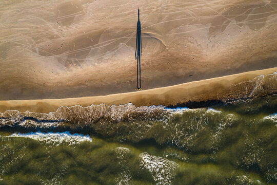 Aerial view of person silhouette shadow standing on Baltic sea shore beach in Klaipeda, Lithuania. Perspective of beautiful nature patterns on surface.