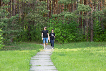 Fototapeta premium A pair of young people walks in the park among beautiful nature