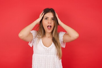 Fototapeta premium Excited overjoyed woman screams after recieving good news, keeps hands on head, can't believe it.