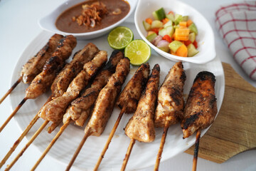 Sate Ayam or Chicken Satay - Indonesian food. Served with peanut sauce and chopped vegetables stock photo