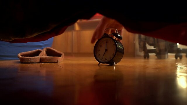 A hand throws a ringing alarm clock