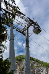Close-up of a cable car support in the mountains, against a cloudy sky, on a summer day.