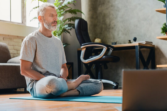 Middle Aged Sport Man Doing Yoga And Fitness At Home Using Laptop