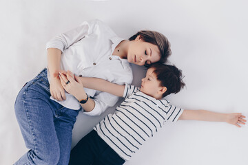 White background. Mom and son are lying nearby. Both eyes are closed and they are pressed against each other. Affection and love