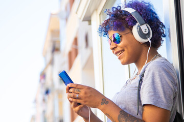 Fototapeta na wymiar afro american latin girl with mobile phone and headphones on the street outdoors
