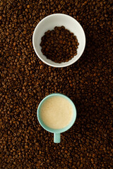 Coffee cup and bowl with coffee beans on a bed of coffee beans